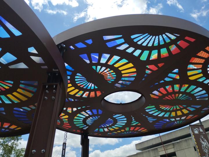 Deux ombrières en acier découpé aux panneaux colorés vues en contre-plongée, parvis de la gare de Saint-Pierre-des-Corps