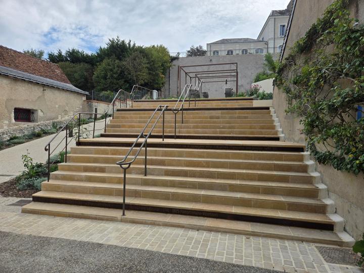 Grand escalier en pierre aux contremarches en acier corten gravées de citations, avec mains courantes métalliques, montant vers la mairie de Véretz