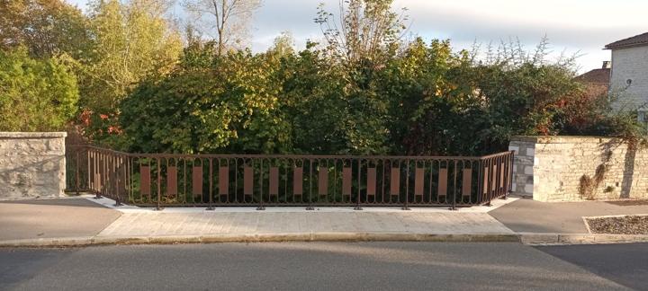 Garde-corps en acier corten à motifs d'arcades le long d'un mur en pierre