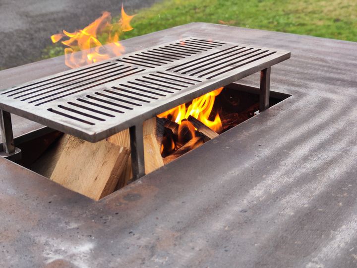 Grille de cuisson en acier posée au-dessus d'un foyer de bois allumé