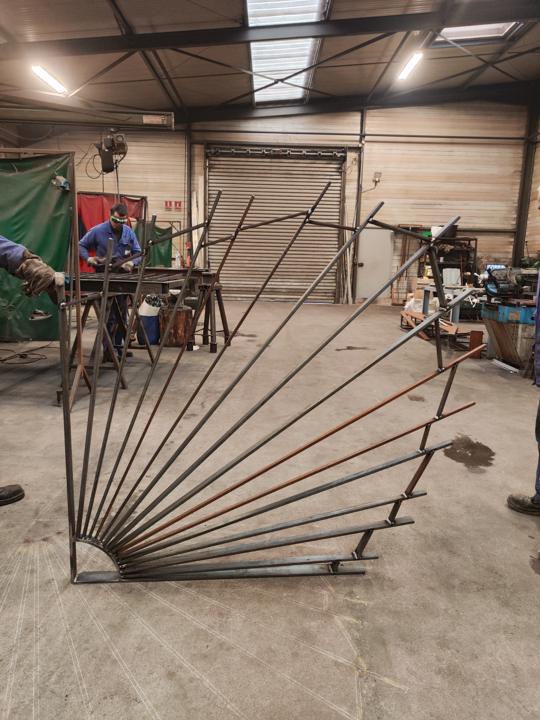 Grille en éventail en fer forgé en cours de fabrication dans l'atelier