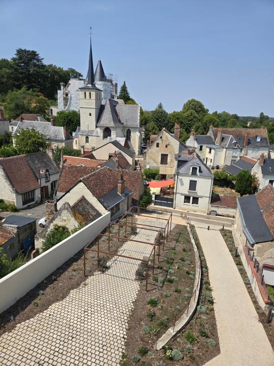 Vue aérienne des pergolas en acier et des cheminements des abords de la mairie de Véretz, avec l'église en arrière-plan