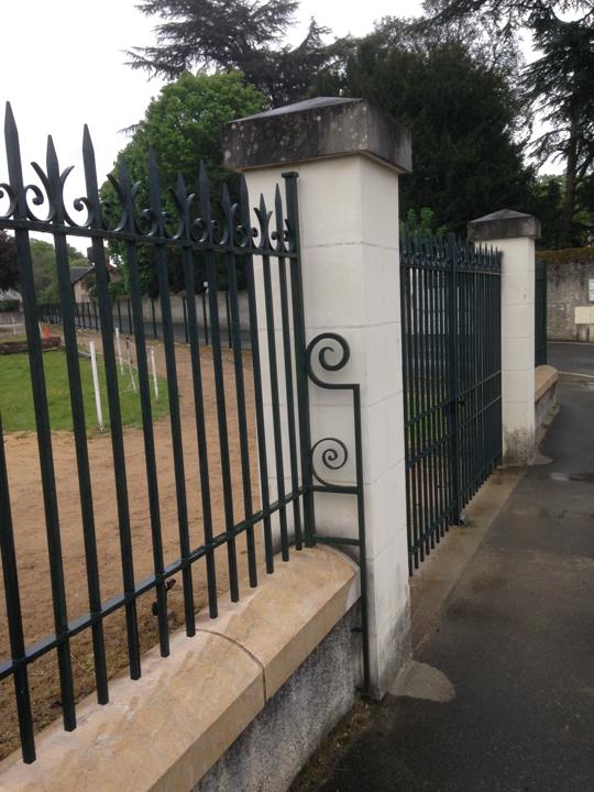 Barreaudage et portail de cimetière en fer forgé à volutes et têtes de lance sur muret