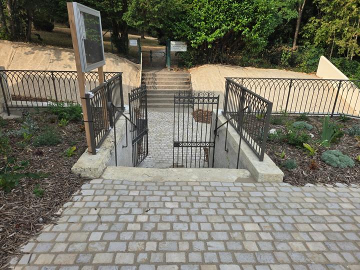 Deux portillons en fer ouvragés entre des garde-corps à arcatures en haut d'un escalier vers le parc de Véretz