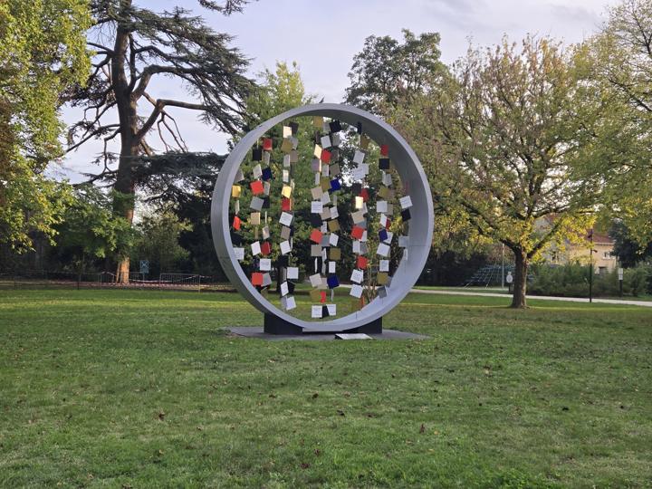 Sculpture monumentale circulaire en métal coloré restaurée, installée sur une pelouse de parc