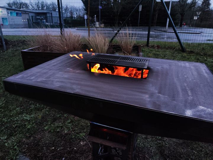 Plateau plancha en acier autour d'un foyer allumé avec grille de cuisson