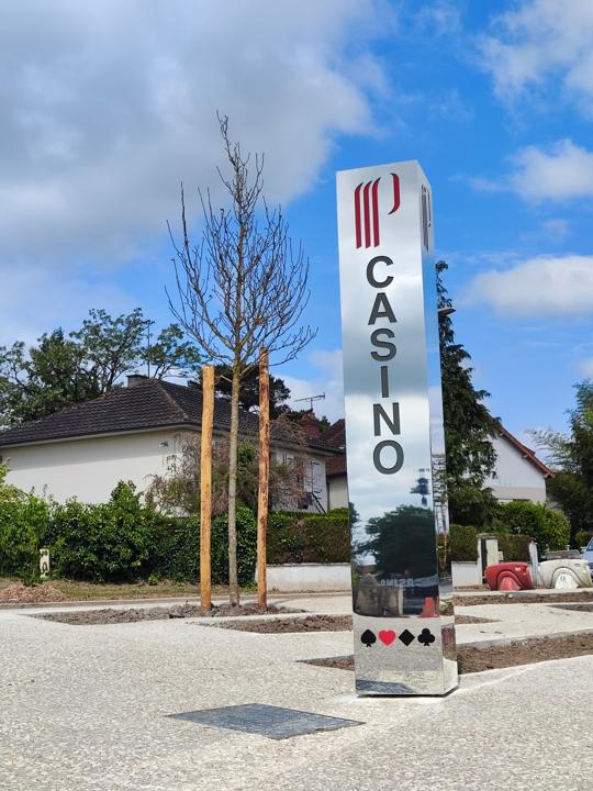 Totem signalétique vertical en inox poli devant un bâtiment